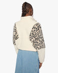Person wearing a white fleece vest with leopard print sleeves on a white background