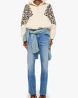 Person wearing a patterned sweater and light blue jeans on a white background