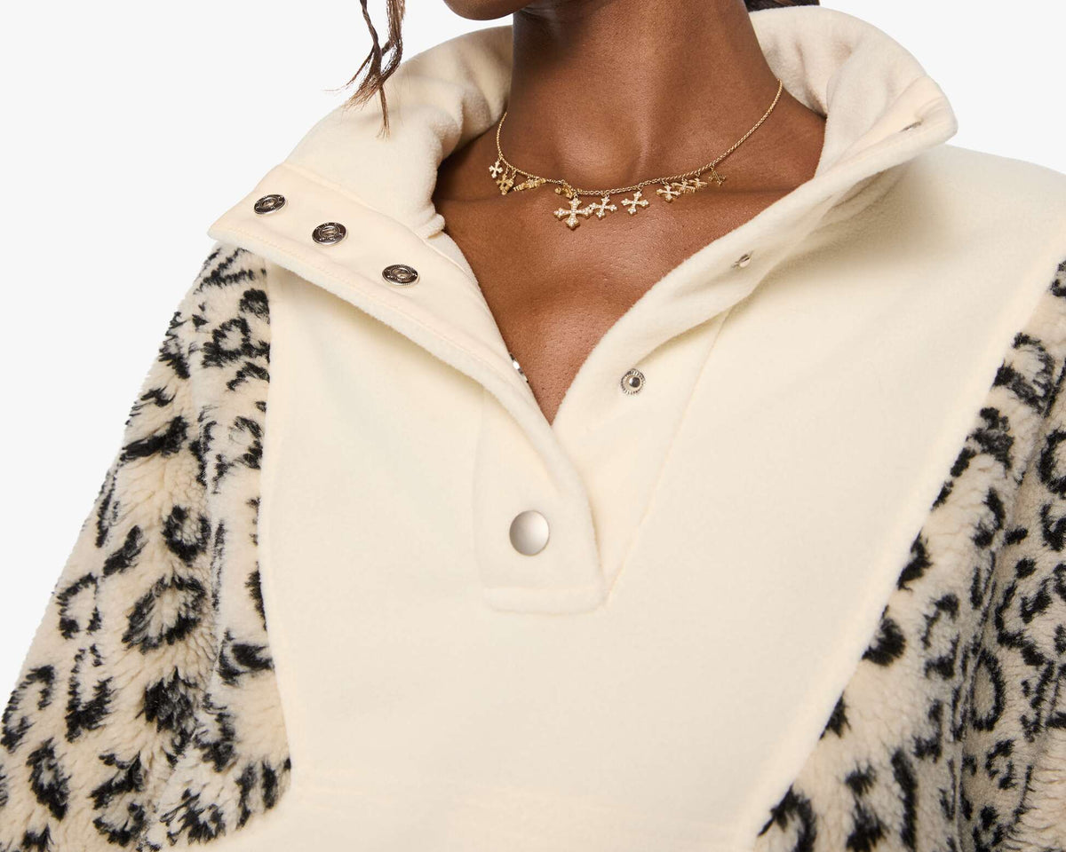 Woman wearing a cream-colored jacket with leopard print sleeves on a white background