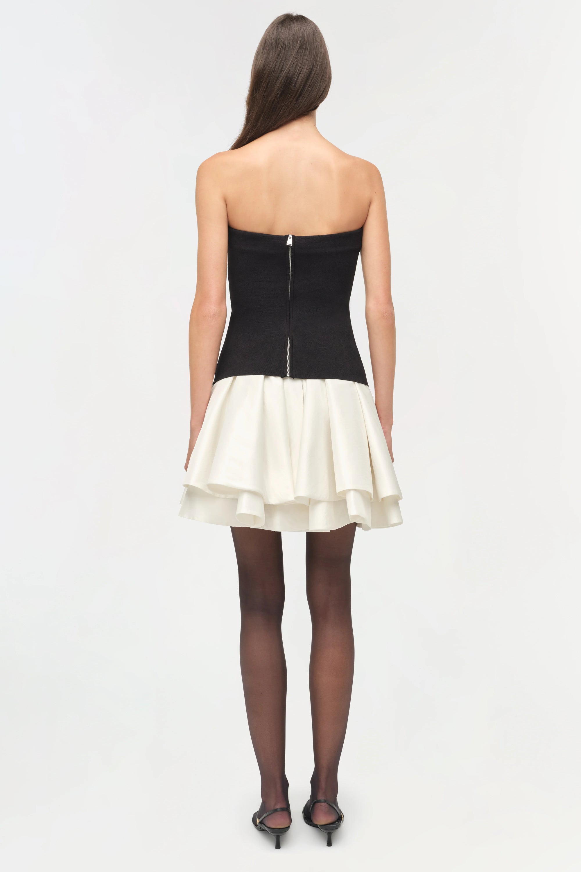 Isabelle Taffeta Knit Mini Dress on a model  holding a black bag with a white background back 