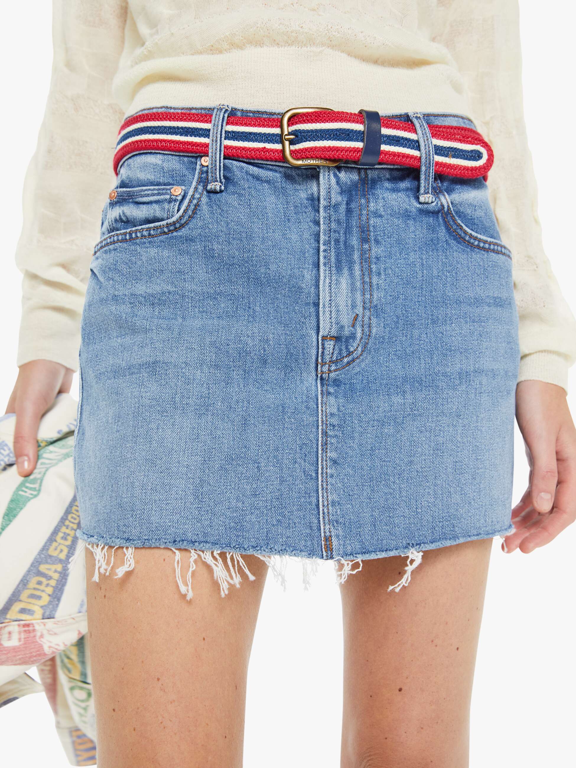 Denim skirt with a striped belt worn by a person, on a white background