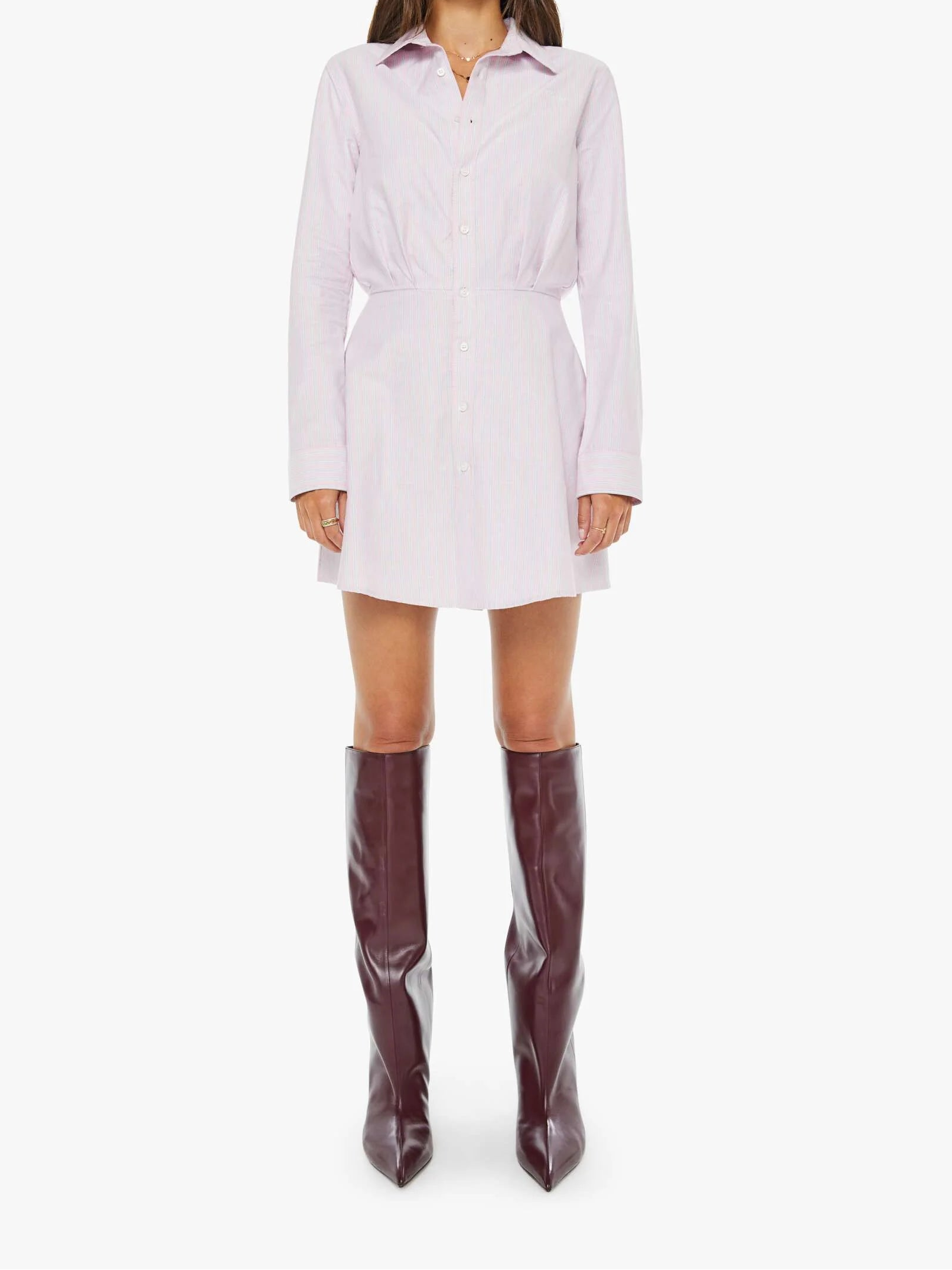 Woman wearing a white shirt dress and brown knee-high boots on a white background