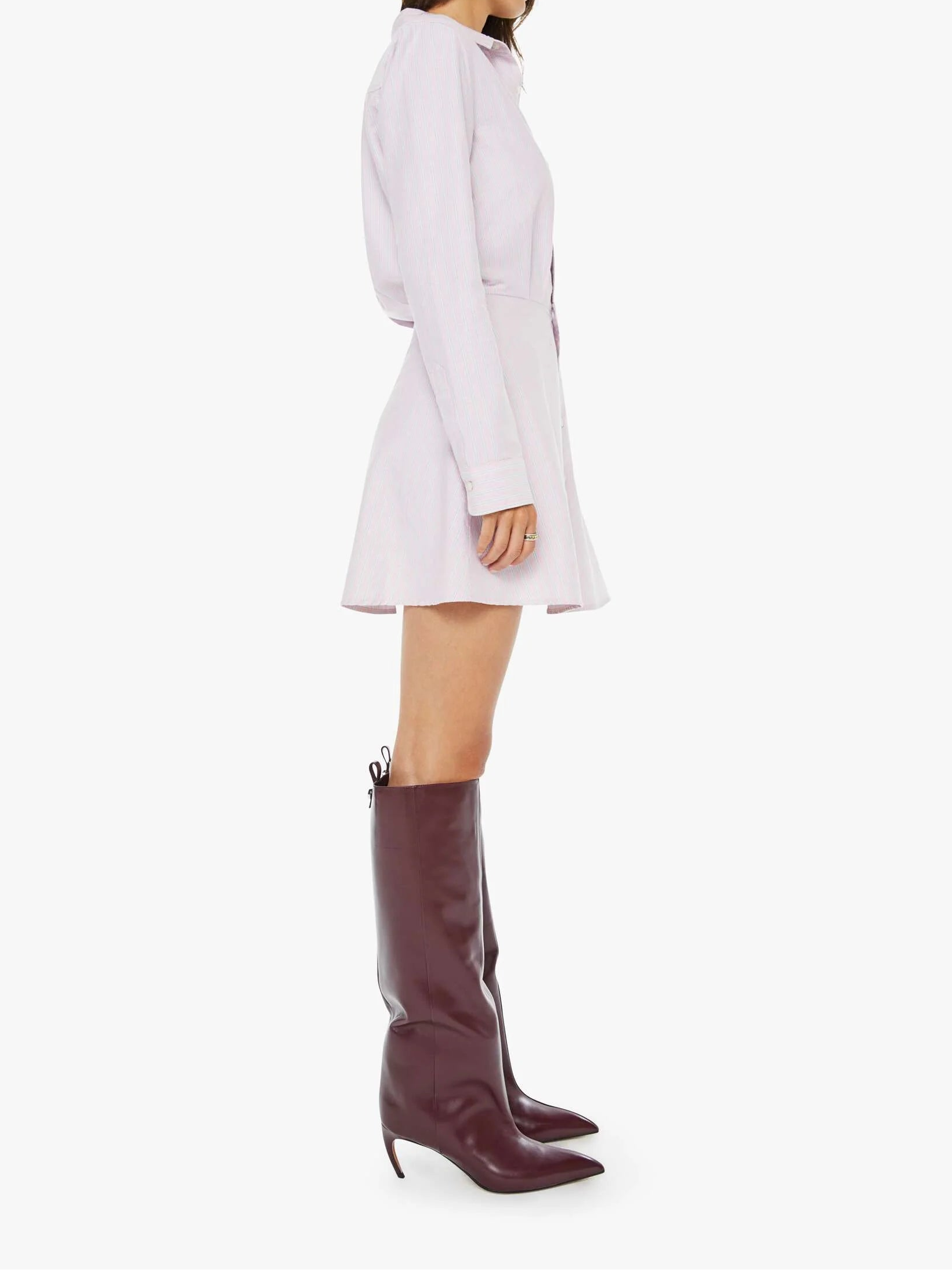 Woman wearing a white dress and burgundy knee-high boots on a white background