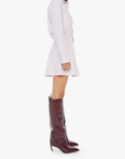 Woman wearing a white dress and burgundy knee-high boots on a white background