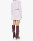 Woman wearing a light purple dress and high boots on a white background