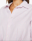 Woman wearing a light pink shirt with a plain background