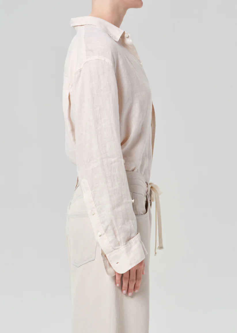 Model wearing a light-colored shirt with long sleeves on a plain background
