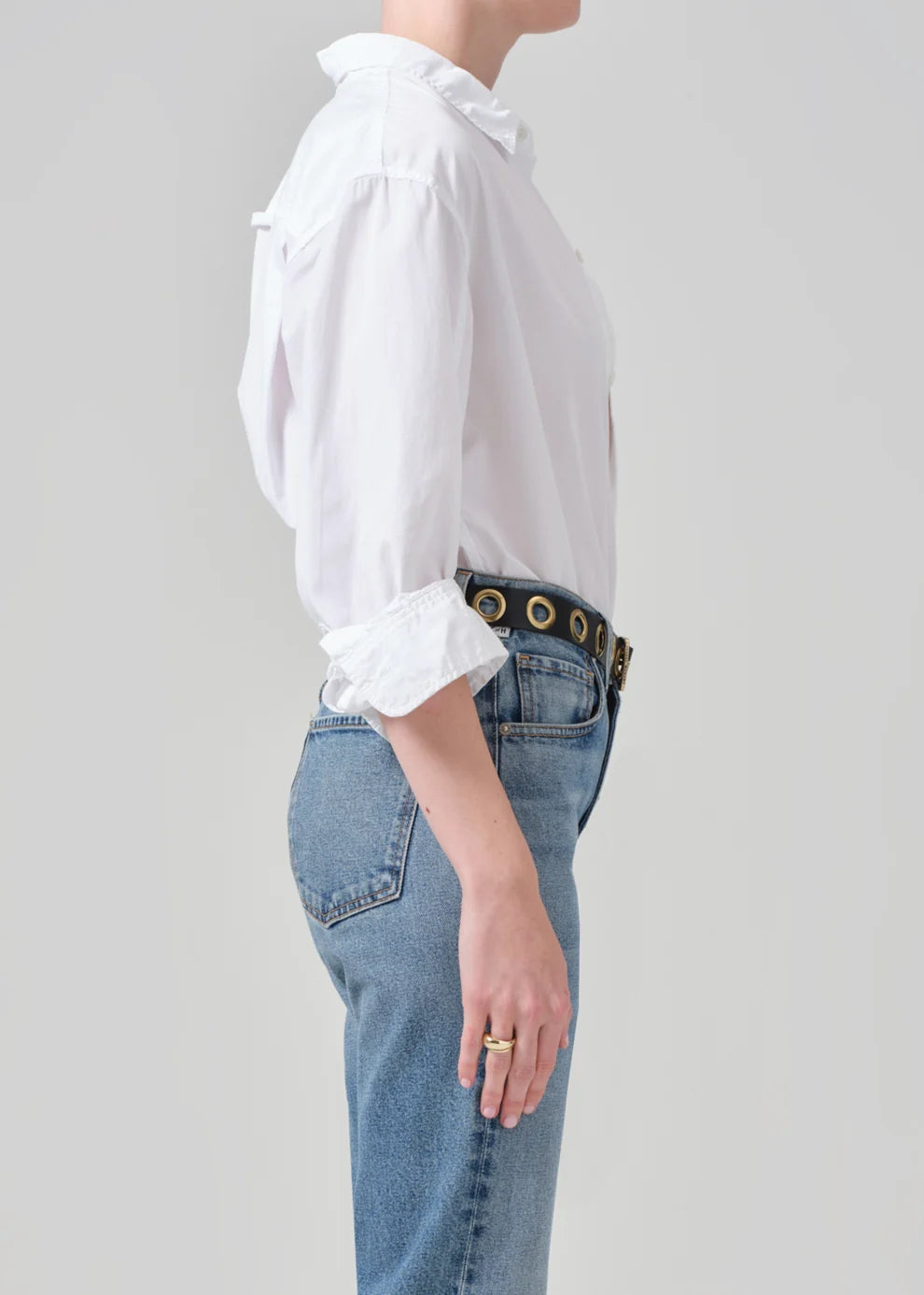 Person wearing a white shirt and blue jeans with a belt on a plain background