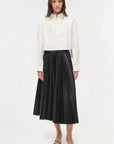 Woman wearing a white blouse and black pleated skirt on a white background