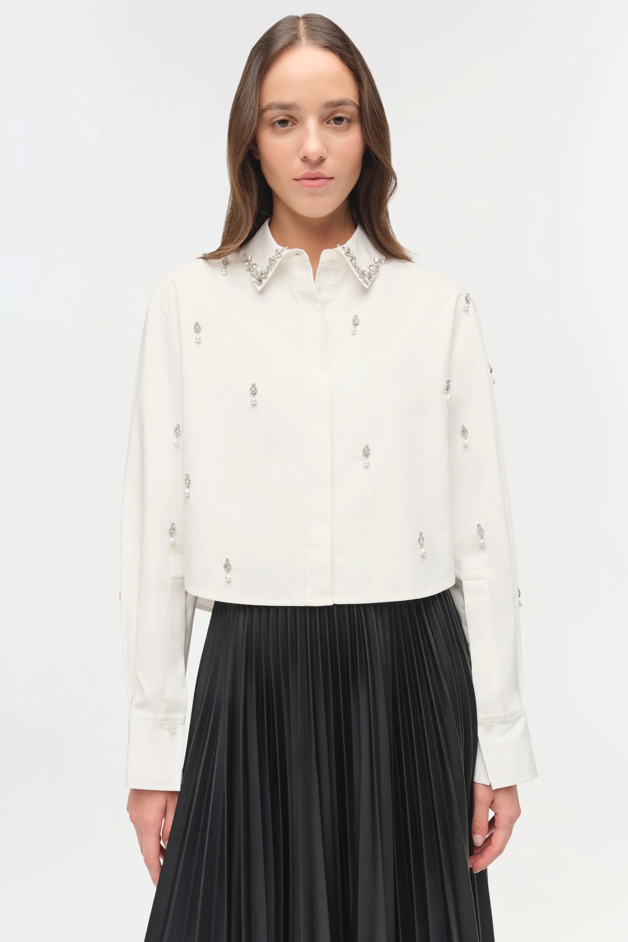 Woman wearing a white blouse with black pleated skirt on a white background