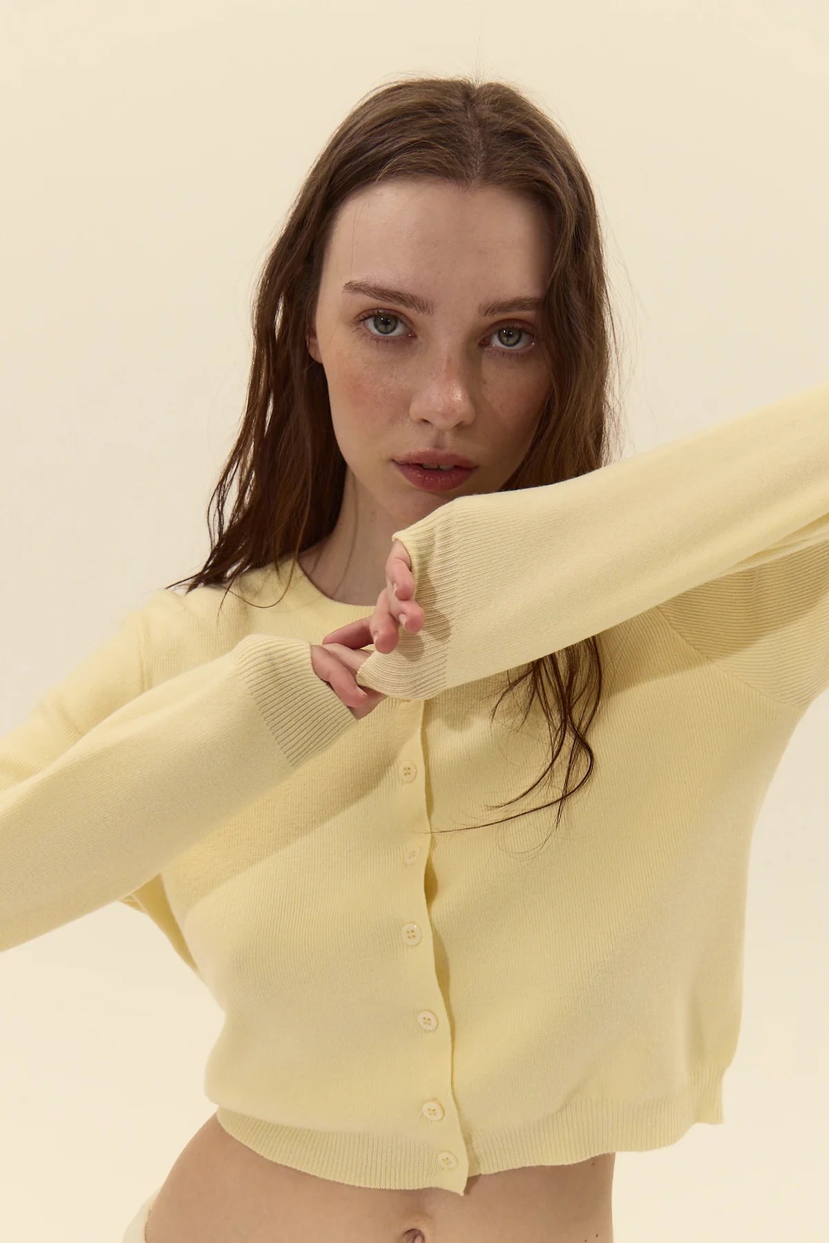 Woman wearing a light yellow cardigan against a plain background