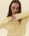 Woman wearing a light yellow cardigan against a plain background