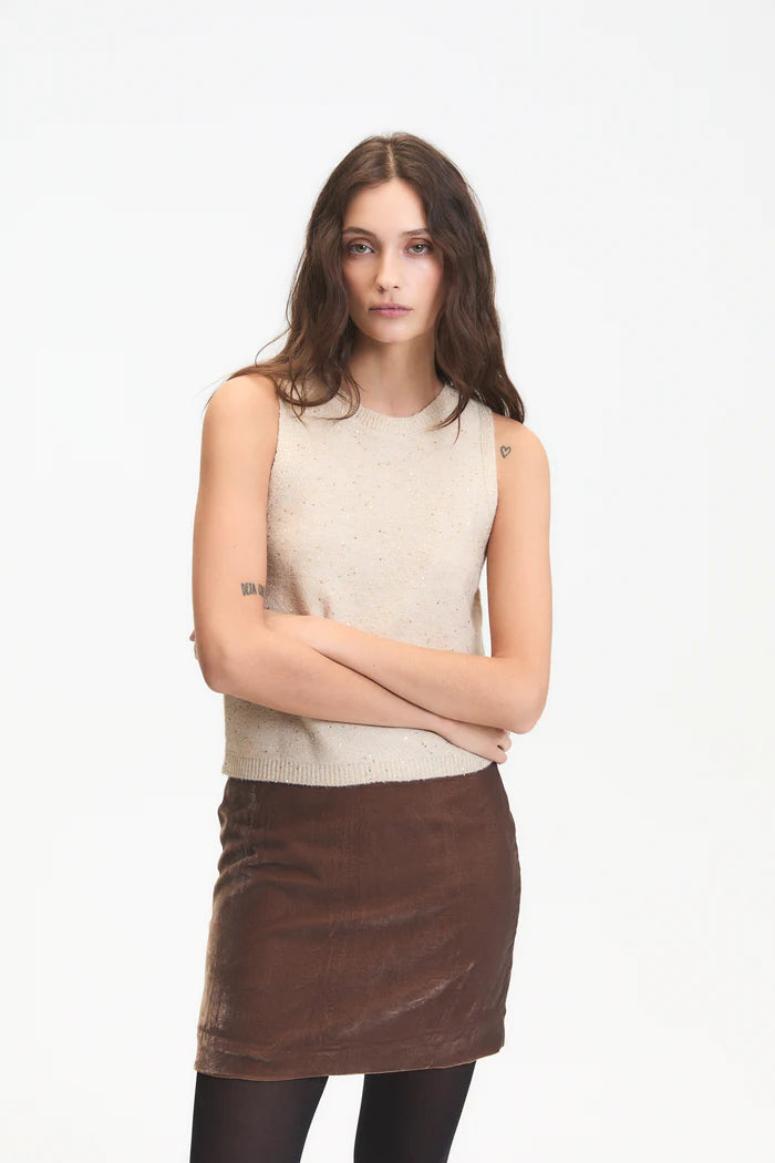 Woman wearing a beige sleeveless top and brown skirt on a white background