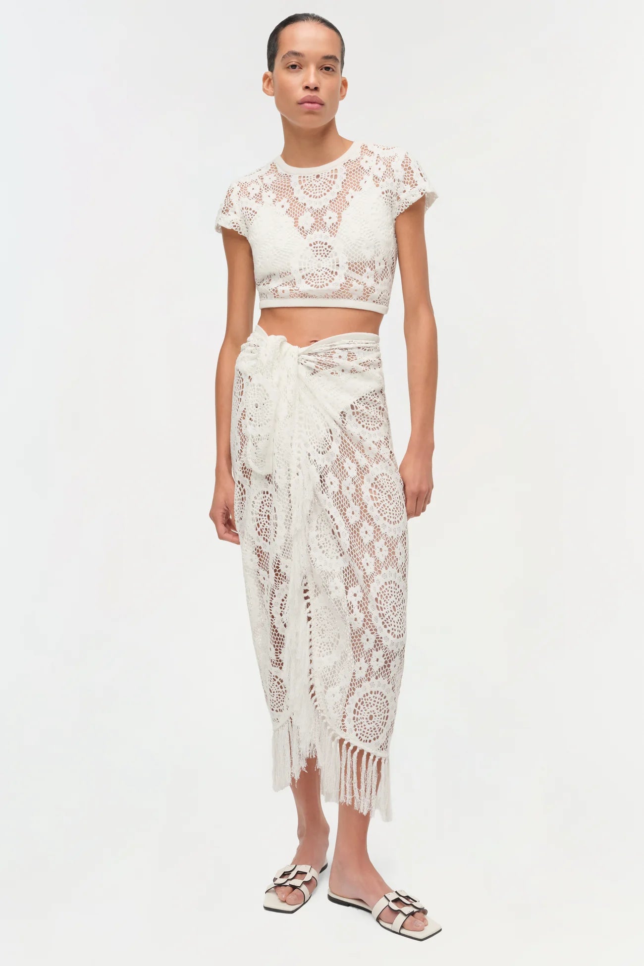 Woman wearing a white lace outfit on a white background