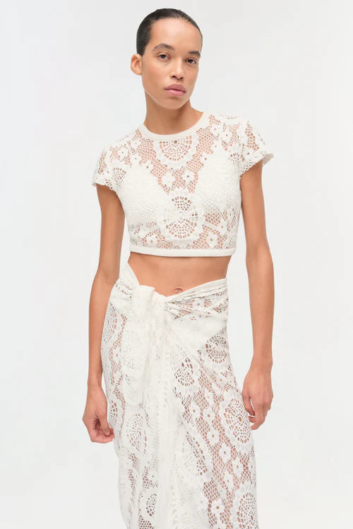 Woman wearing a white lace top and skirt on a plain background