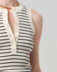 Close-up of a person wearing a black and white striped sleeveless top with a plain background
