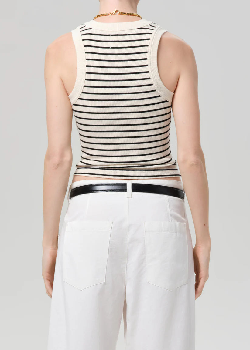 Person wearing a black and white striped tank top with a plain background