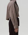 Person wearing a brown checkered shirt with a plain background, side