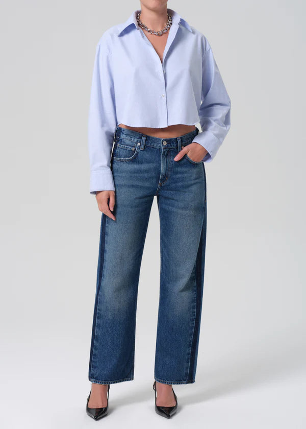 Person wearing a light blue shirt and blue jeans on a white background