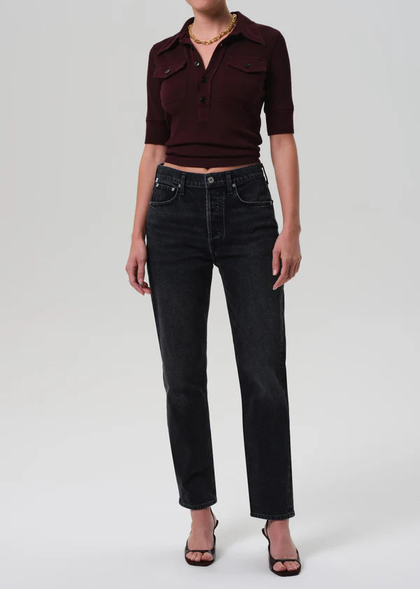 Person wearing a burgundy cropped shirt and black jeans on a white background front view