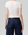 A model shown from the back wearing a fitted off-white short-sleeve t-shirt and dark blue wide-leg jeans with a black belt, against a light gray studio background.