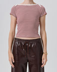 A model wearing a burgundy and white striped short-sleeve top with dark brown faux-leather wide-leg pants, photographed against a light gray studio background.