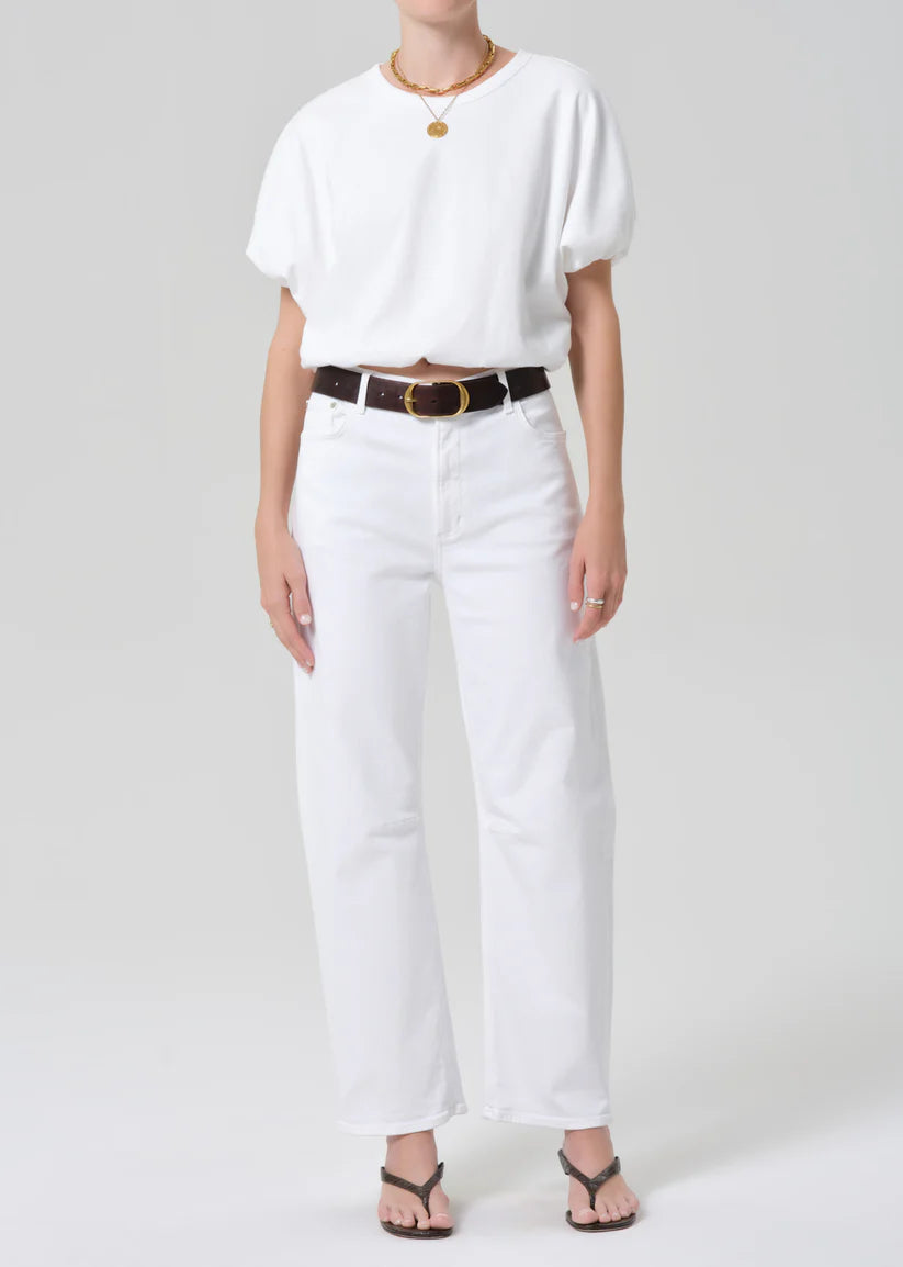 Person wearing a white outfit with a belt on a plain background