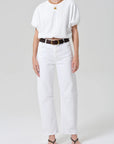 Person wearing a white outfit with a belt on a plain background