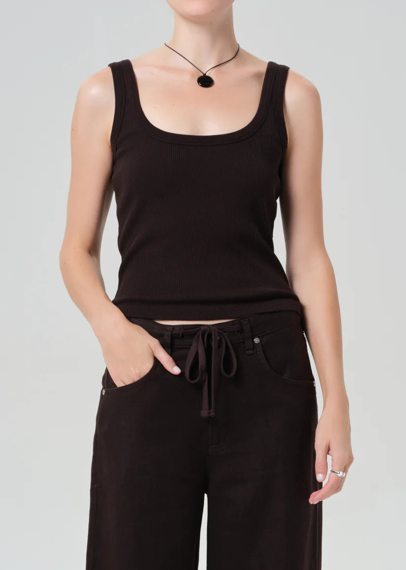 Person wearing a brown tank top and black pants on a light gray background