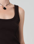 Person wearing a brown tank top and necklace on a plain background