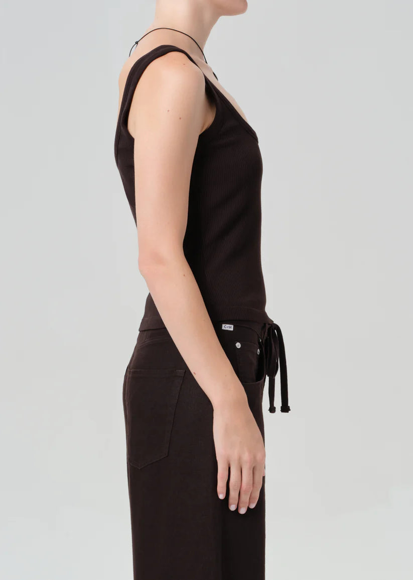 Person wearing a brown sleeveless top and pants on a light gray background