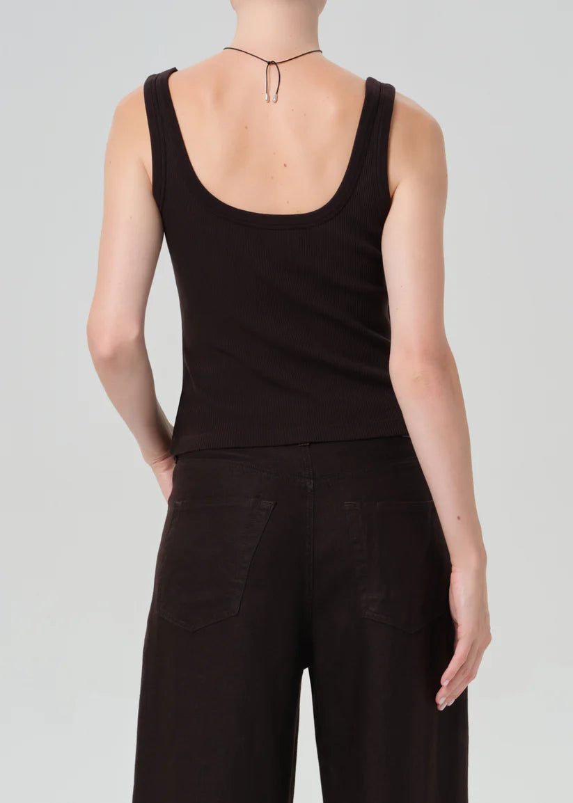 Person wearing a brown tank top and pants on a plain background