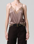 Woman wearing a brown lace-trimmed top and black pants on a gray background
