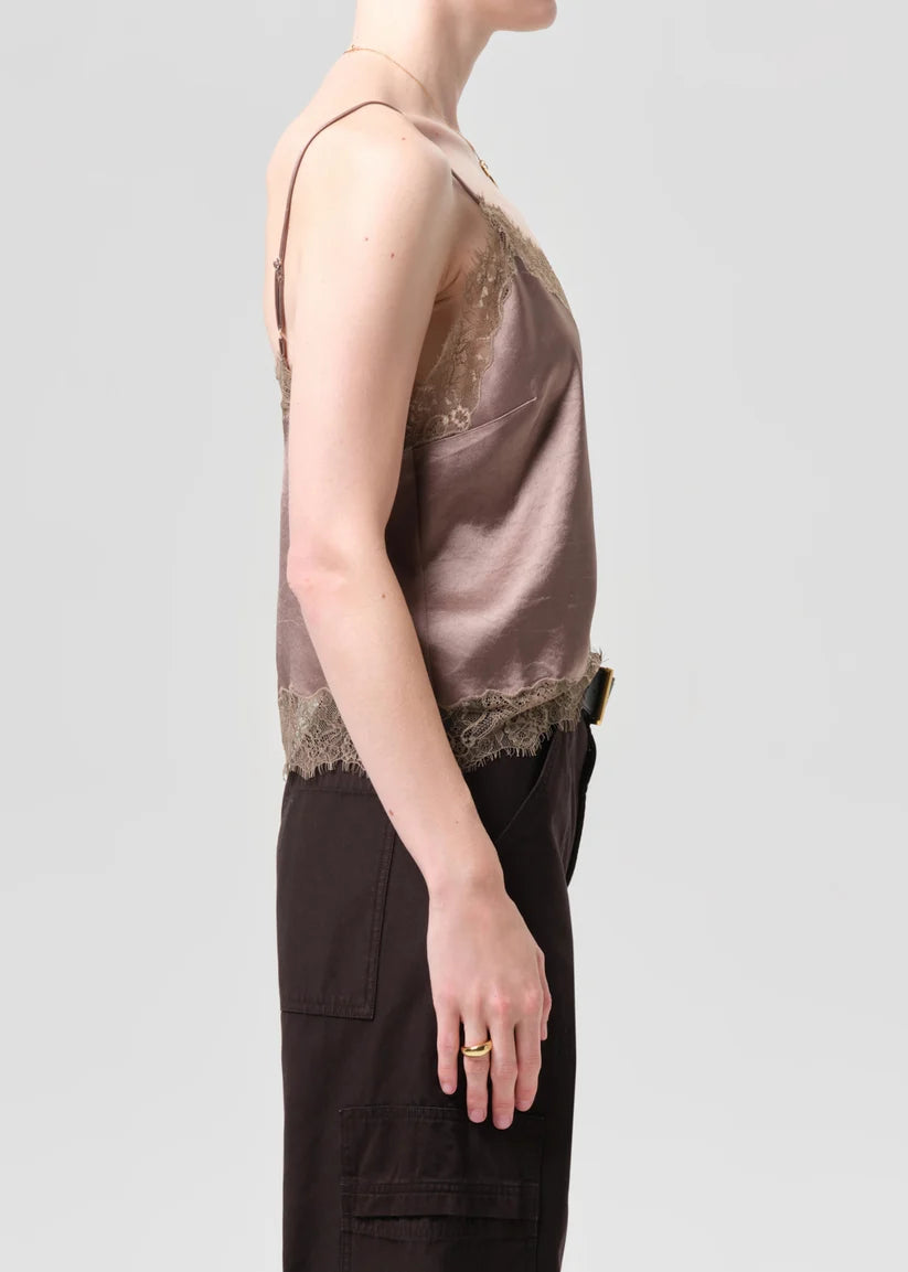 Person wearing a brown lace-trimmed top and dark pants on a light gray background