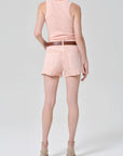 Person wearing a pink sleeveless top and shorts set on a white background