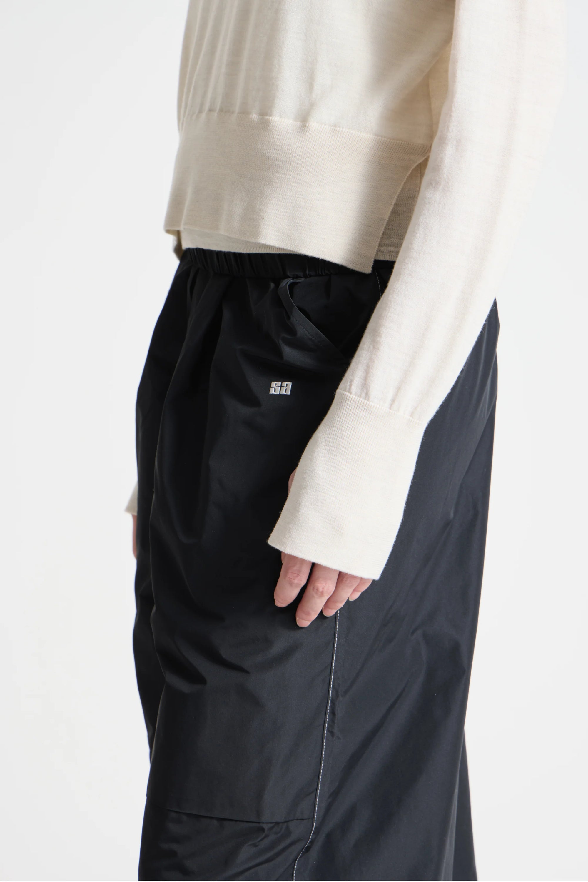 Person wearing black pants with a visible brand logo on a white background