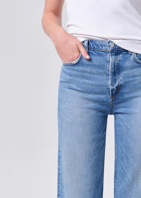 Person wearing light blue jeans with a plain background