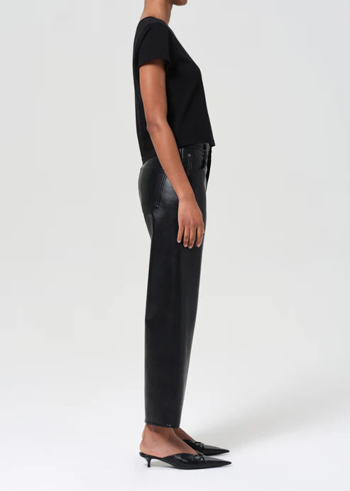 Person wearing black leather pants and a black top on a white background