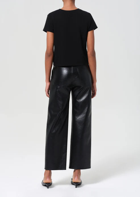 Person wearing black leather pants and a black top on a white background