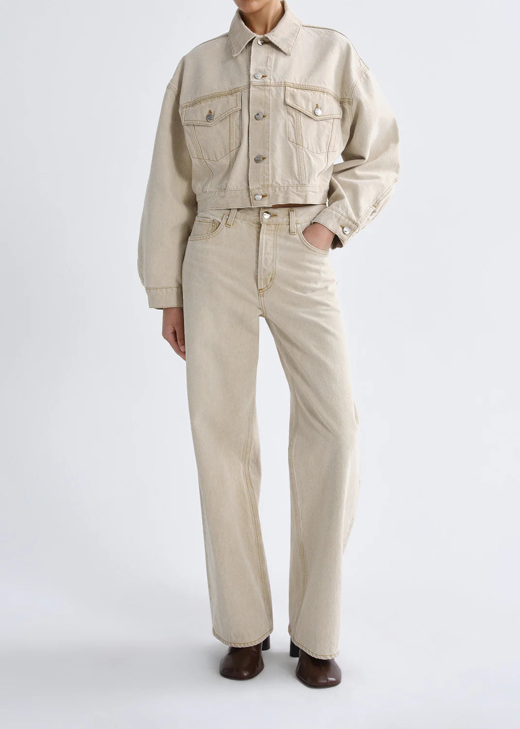 Person wearing a beige jacket and pants on a white background