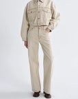 Person wearing a beige jacket and pants on a white background