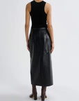A model shown from the back wearing a black sleeveless ribbed top and a black leather midi skirt, paired with brown heeled boots, against a light gray studio background.