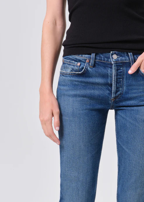 Person wearing blue jeans and a black top on a light gray background