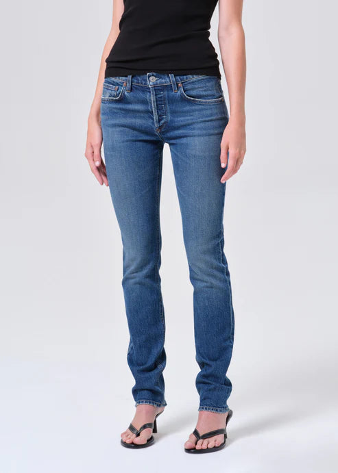 Person wearing blue jeans and a black top on a white background