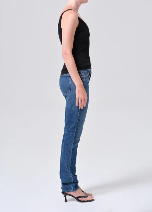 Person wearing blue jeans and a black top on a white background