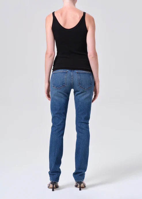 Person wearing blue jeans and a black tank top on a white background
