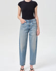 Person wearing a black top and light blue jeans on a white background