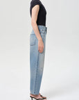 Person wearing light blue jeans and a black top on a white background