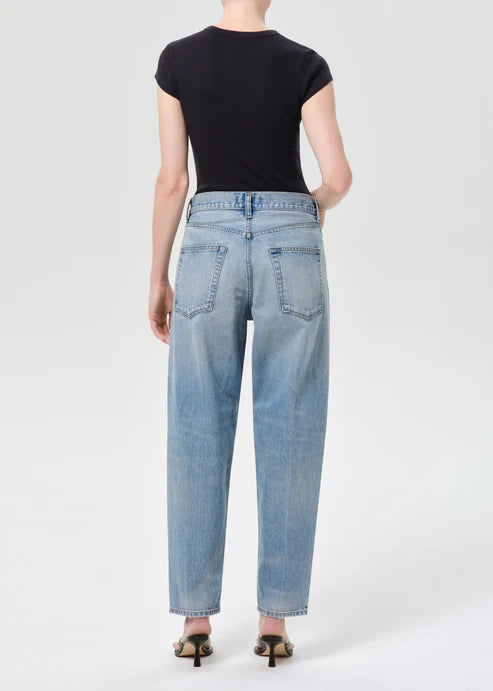 Person wearing light blue jeans and a black top on a white background