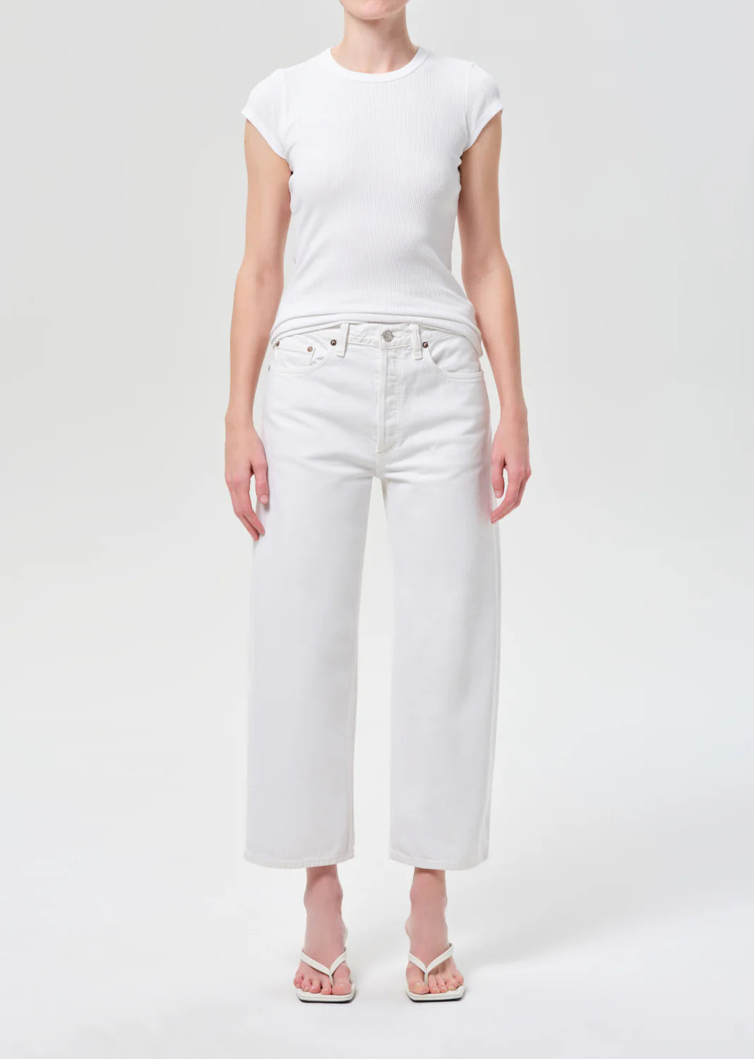 Person wearing a white t-shirt and white jeans on a light gray background